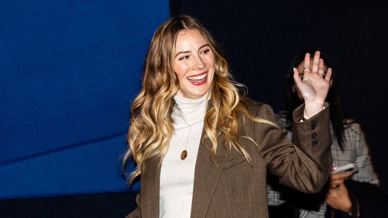 Emily Henry waving while on stage at a book event