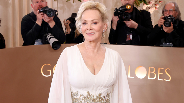 Jean Smart in a white gown with a gold belt around her waist and her hair swept up
