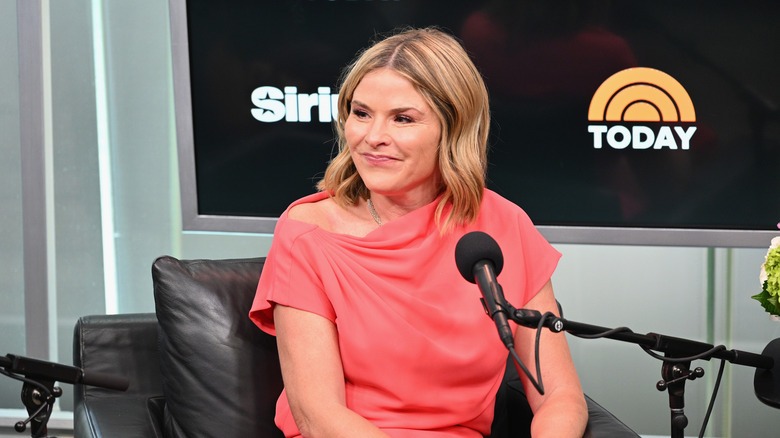 Jenna Bush Hager speaking into a podcast microphone while wearing an orange dress
