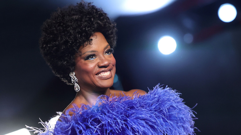 Viola Davis smiling at a red carpet event while wearing a feathery, off-the-shoulder garment