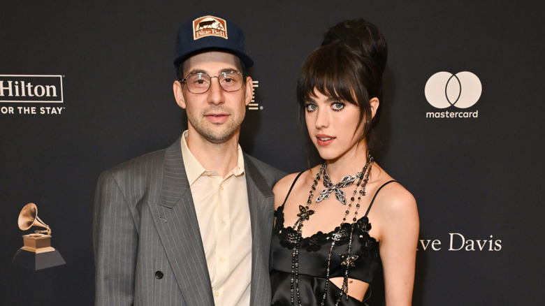 Jack Antonoff in a ball cap and Margaret Qualley in a black dress at an event