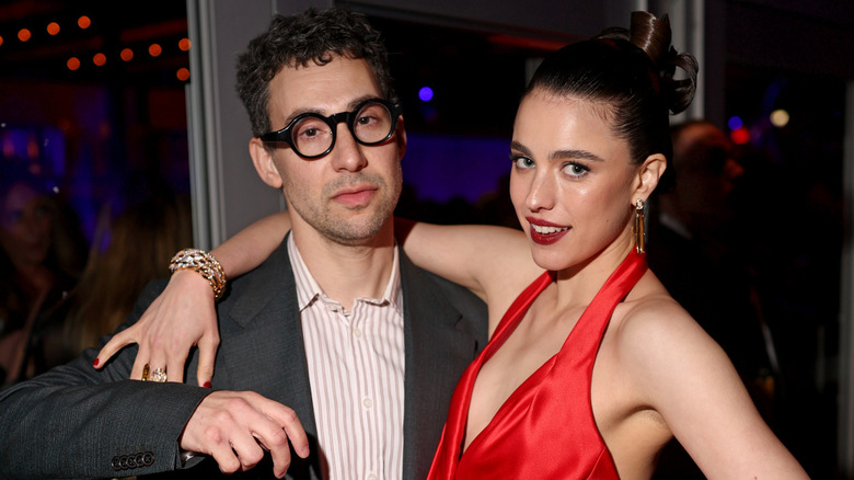 Margaret Qualley in red and Jack Antonoff in dark glasses at an event