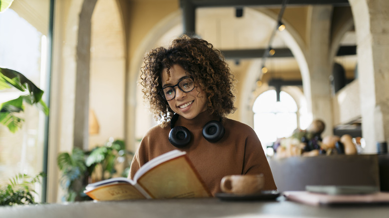 Young woman enjoying a book and coffee in a coffee shop
