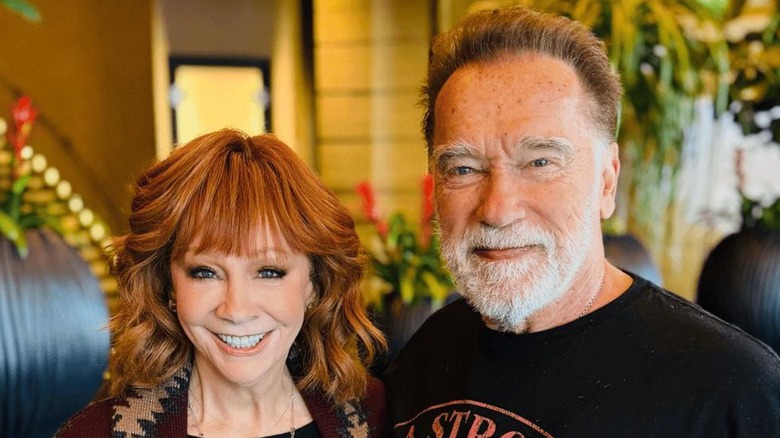 Reba McEntire smiling with Arnold Schwarzenegger