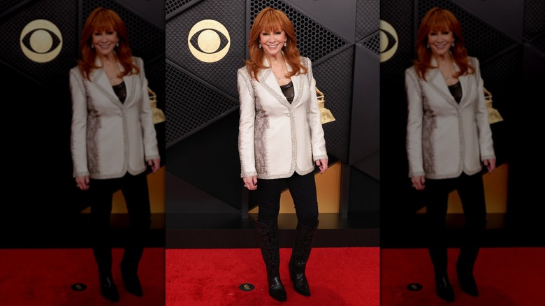 A full-body image of Reba McEntire at the 2026 Grammys, showing her silver blazer and black pants