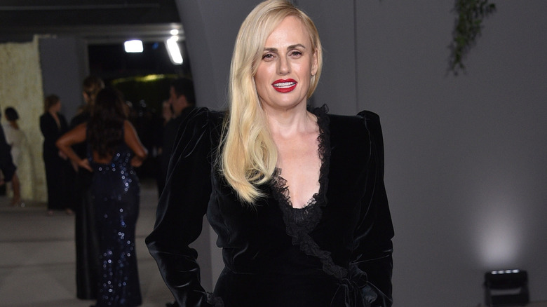 Rebel Wilson in a black, long sleeve dress at an event