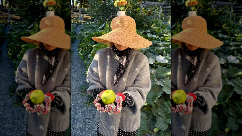 Pamela Anderson holding an apple in her garden