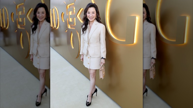 Michelle Yeoh smiling at a Gold House event while wearing a matching mini-skirt and blazer