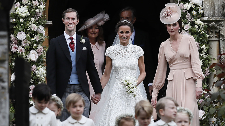 Pippa Middleton and James Matthew on their wedding day with Catherine, Princess of Wales in the background