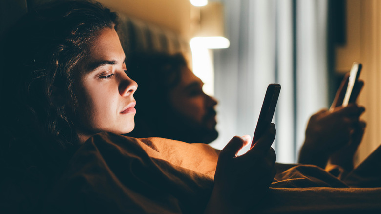 bored couple on phones in bed