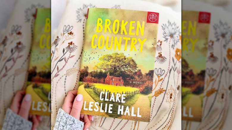Hand holding copy of the novel "Broken Country" on by Clare Leslie Hall