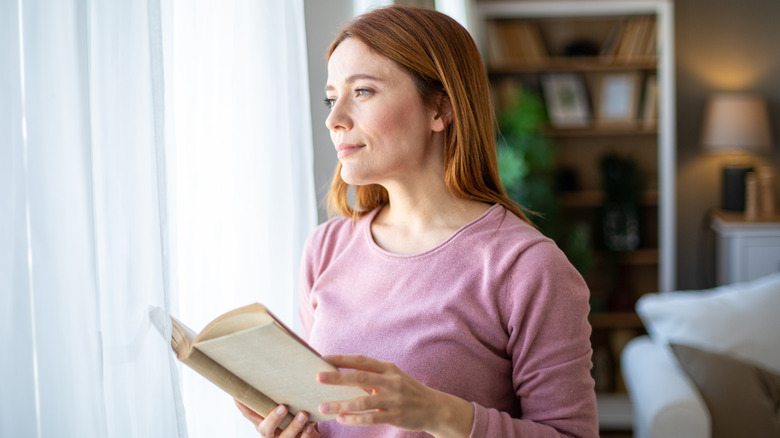 Woman in a pink sweater holding a book