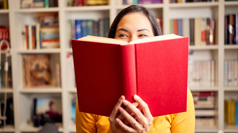 Woman smiling behind book