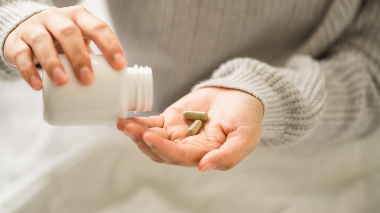 Woman puts vitamins into hand