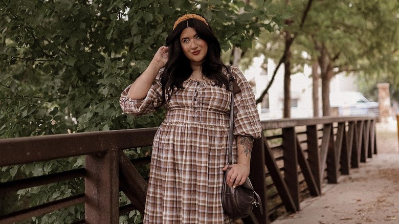 Woman in plaid dress and headband posing in park