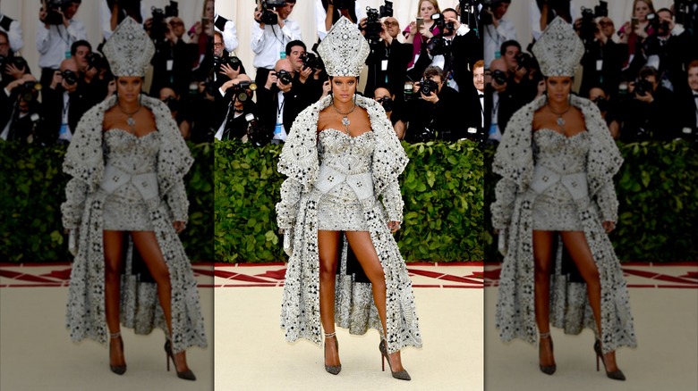 Rihanna at the 2018 Met Gala in a rhinestone and pearl encrusted mini dress with cape and head piece