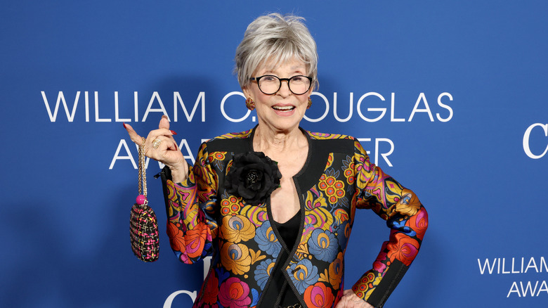 Rita Moreno smiles wearing a colourful jacket