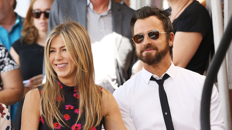 Jennifer Aniston sitting with Justin Theroux and laughing