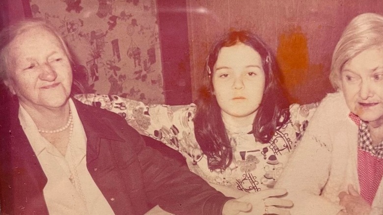 Rosie O'Donnell with a neutral expression while posing between her grandmothers in 1975