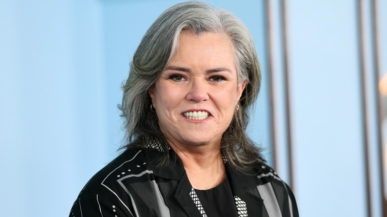 Rosie O'Donnell posing on the red carpet in front of a blue background