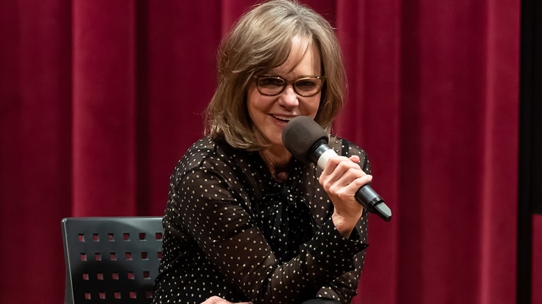 Sally Field in a spotty silk blouse holding a mic