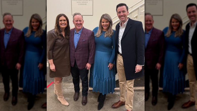 Sarah Huckabee Sanders wearing a brown shift dress and knee-high suede boots while posing with three other people