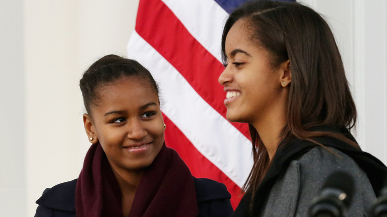 Malia and Sasha Obama onstage with an American flag behind them