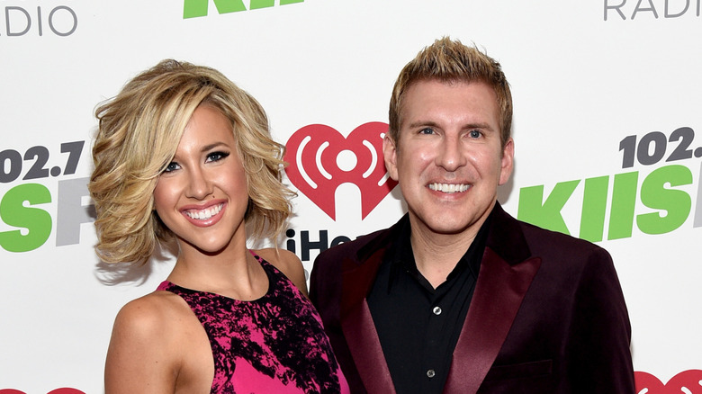 Savannah and Todd Chrisley smiling together on a red carpet