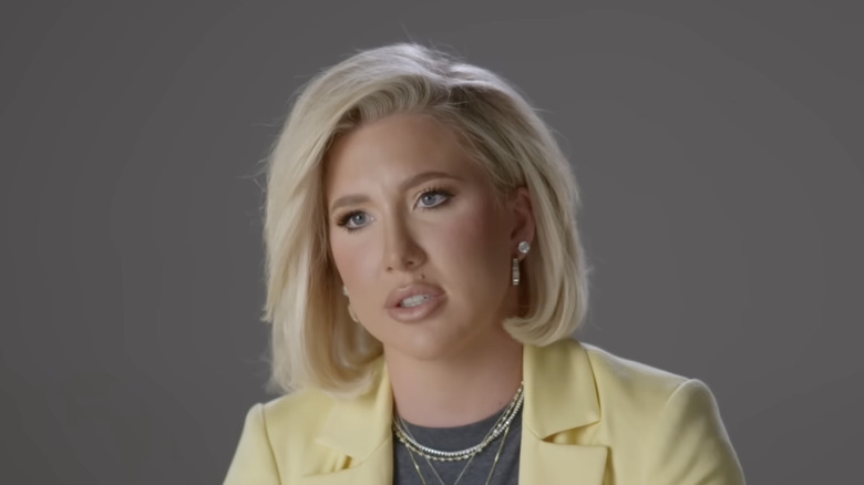 Savanna Chrisley wearing a yellow blazer, giving an interview in front of a gray background