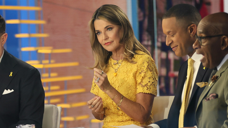 Savannah Guthrie sits with a straight face wearing a yellow dress