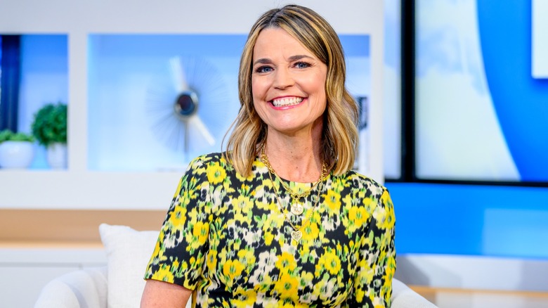 Savannah Guthrie smiling in the "Today" studio in a black, yellow, and white floral dress