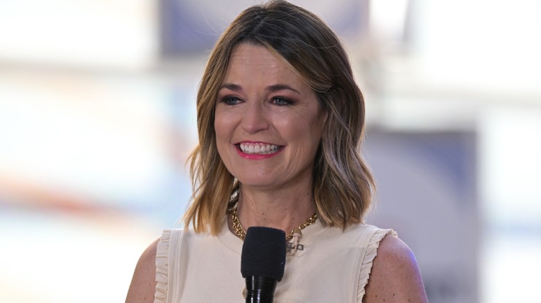 Savannah Guthrie slightly smiling while holding a microphone