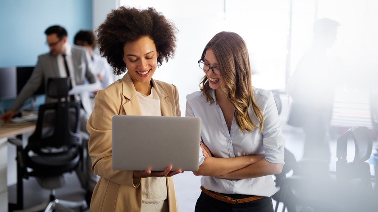 Women smiling while looking at a laptop