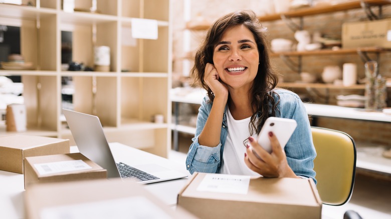 Woman smiling and holding her phone at work