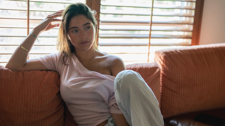 A photo of Lola Consuelos sitting on a sofa with one hand on her head
