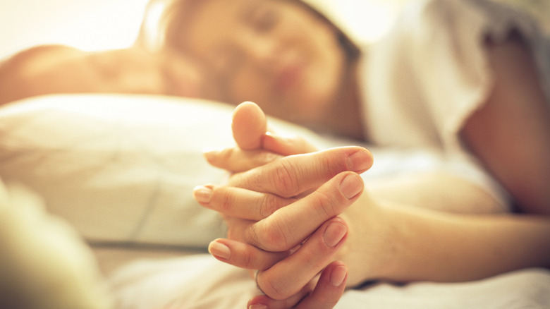 Couple holds hands in bed