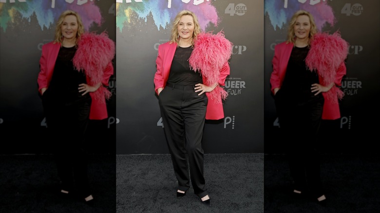 Kim Cattrall on the red carpet wearing all black with a hot pink jacket