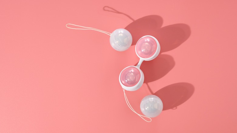 Four Ben Wa balls on pink background