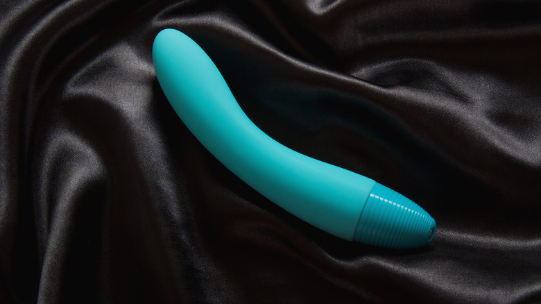 Blue vibrator on black silk sheets