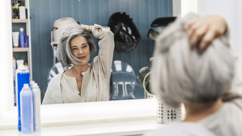 an older woman admiring her short haircut in the salon mirror
