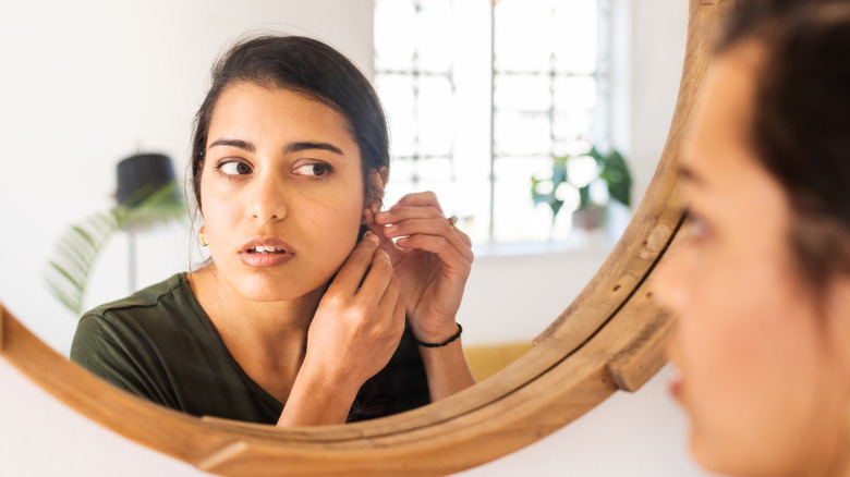 Adjusting earrings in mirror