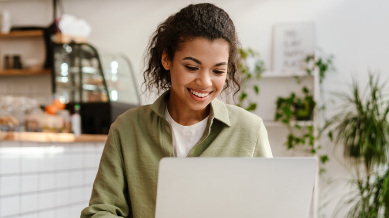 A woman on a laptop, smiling