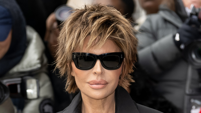 Lisa Rinna posing at an event in sunglasses and an all-black outfit