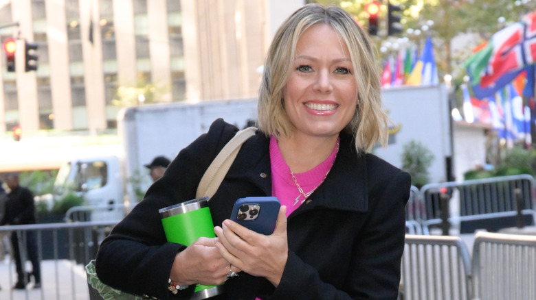 Dylan Dreyer pictured smiling in NYC while carrying a travel mug and smart phone