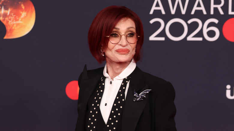 Sharon Osbourne on the red carpet in round tinted glasses and a black suit jacket
