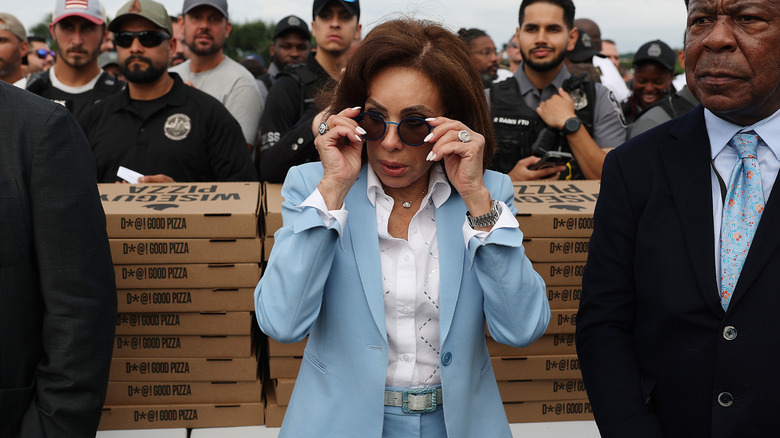 Jeanine Pirro putting on sunglasses while wearing a powder blue suit