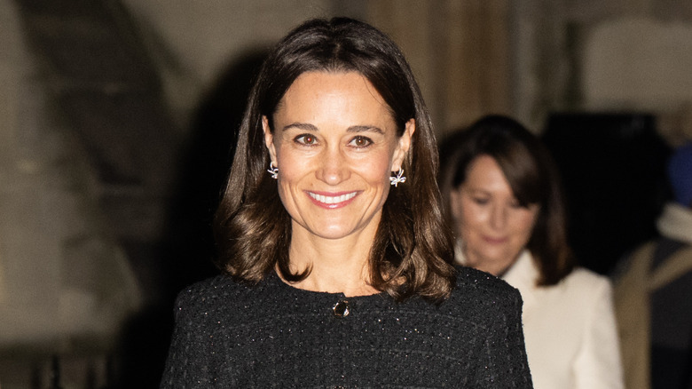 Pippa Middleton in a black dress at an event smiling at the camera