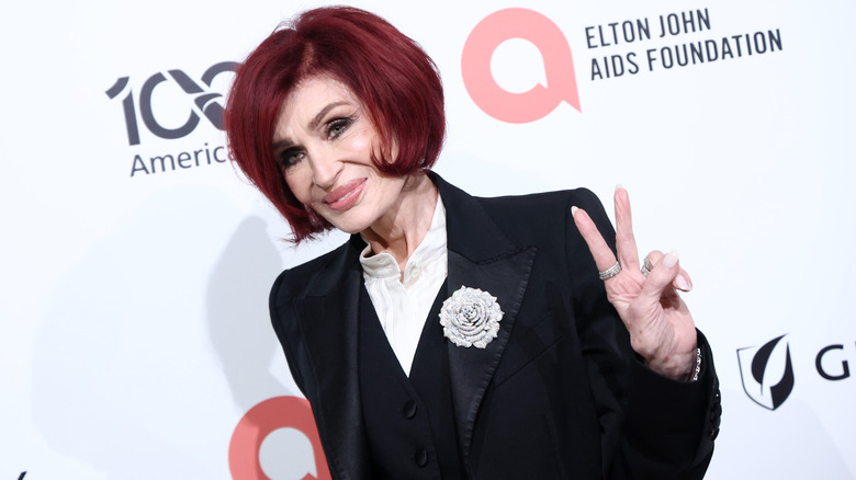 Sharon Osbourne smiles and puts the peace sign up on the red carpet in 2026