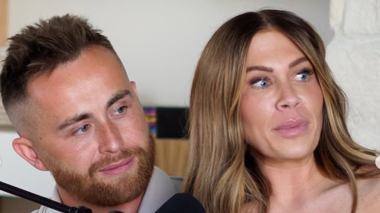 Jessi Draper and Jordan Ngatikaura smile behind a microphone