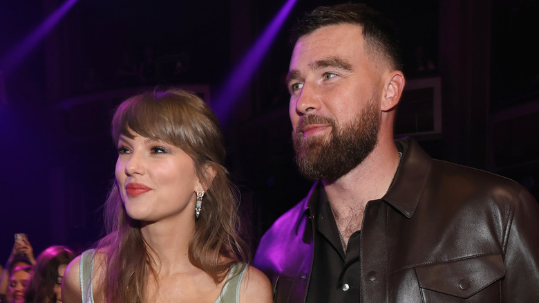 Taylor Swift standing next to Travis Kelce at an awards show
